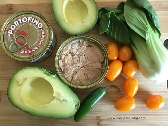 An open can of tuna with bok choy, avocado and cherry tomatoes