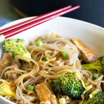 a close up of a bowl of beef and broccoli stir fry over noodles