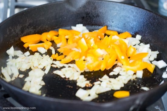 cooking yellow peppers and onion in a cast iron skillet