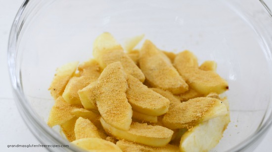 The cut apple slices with blond coconut sugar and cinnamon in a bowl.