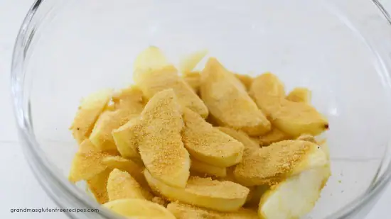 cut apple slices with blond coconut sugar and cinnamon in a bowl