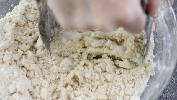 Using a pastry blender to cut butter into the sugar ingredients.