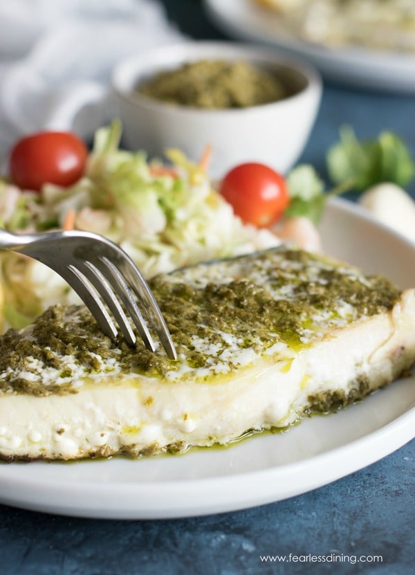 A fork cutting into a halibut steak.