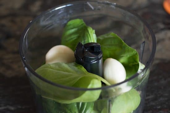 Fresh basil and garlic cloves in a cuisinart.