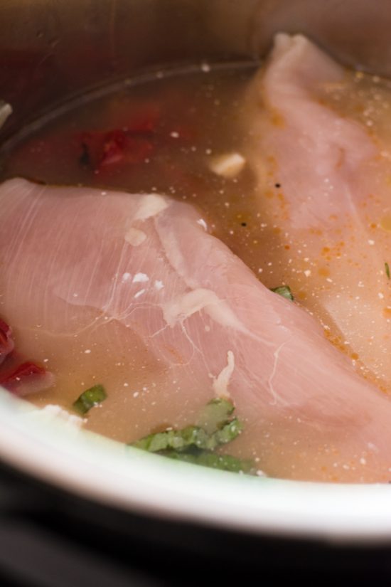 Raw chicken and ingredients in an instant pot.