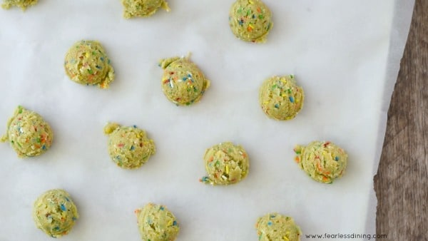 Funfetti cookie dough balls on a baking sheet.