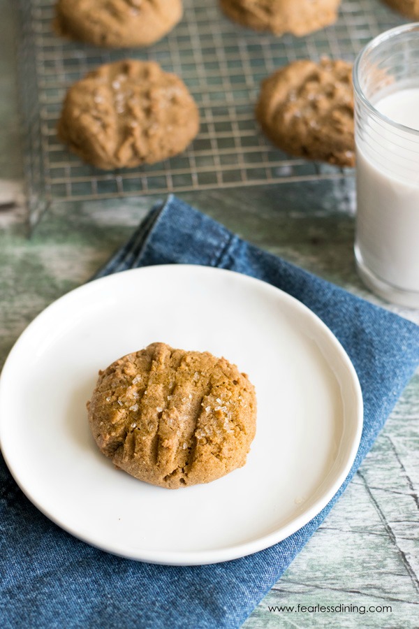 A molasses cookie on a plate. The rack of cookies is behind the plate.