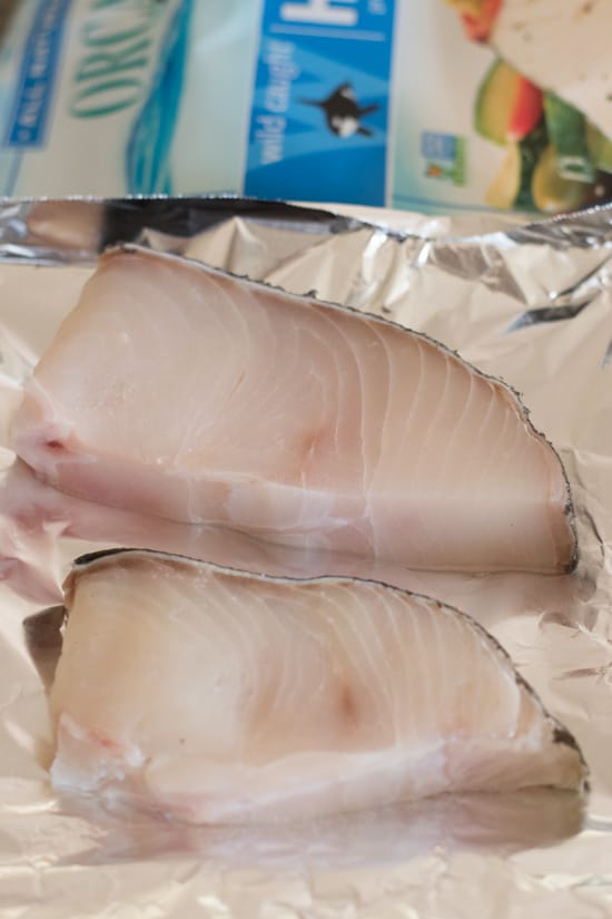 A photo of raw halibut steaks on a piece of foil.