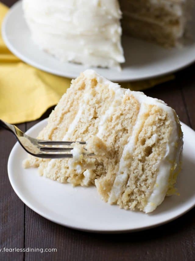 A fork cutting into a slice of lemon layer cake.