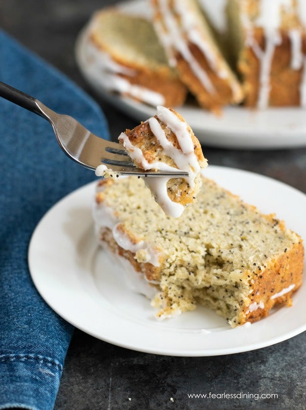 A fork holding up a bite of lemon poppy seed cake.