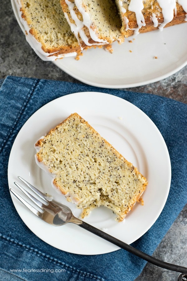 a slice of lemon poppy seed cake on a white plate with a bite taken out.