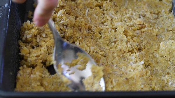 Using a large spoon to press the crust to a pan.