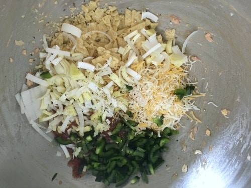 Corn chips, leeks, cheese and green pepper in a bowl.