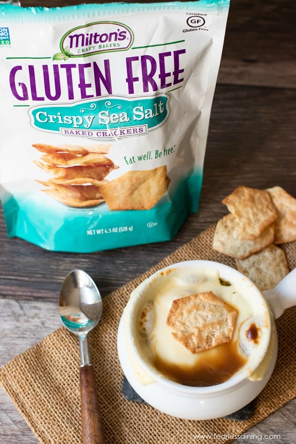 The top view of a bowl of onion soup with a cracker on top of the cheese.