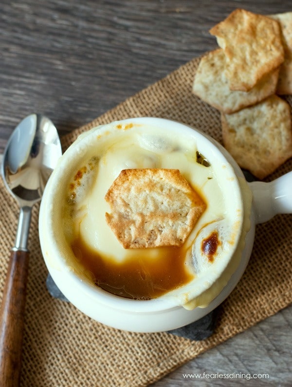 The top view of a bowl of onion soup on a tablecloth.