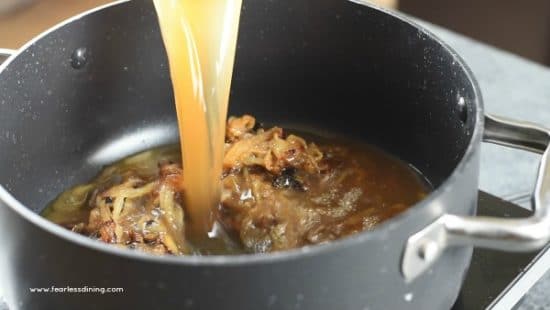 Pouring beef broth into the caramelized onions.