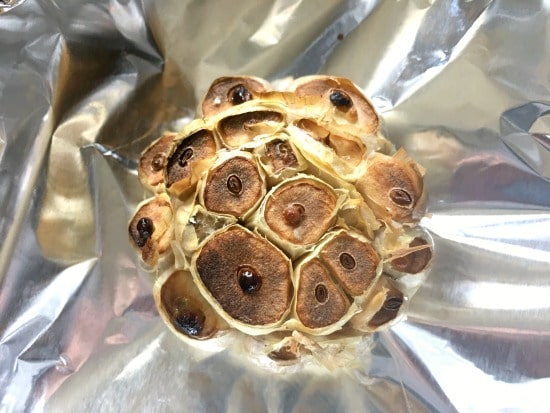 A roasted head of garlic on foil.