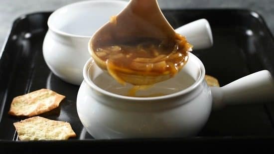 Spooning soup into a bowl.