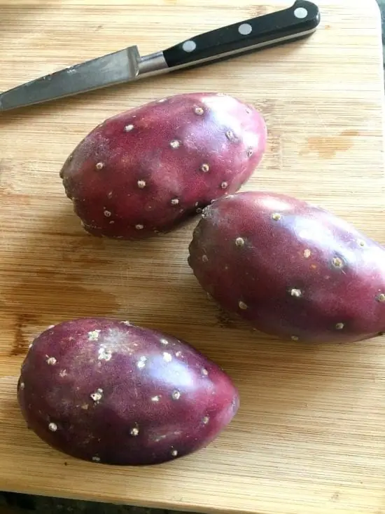 whole prickly pear cactus fruit on a cutting board