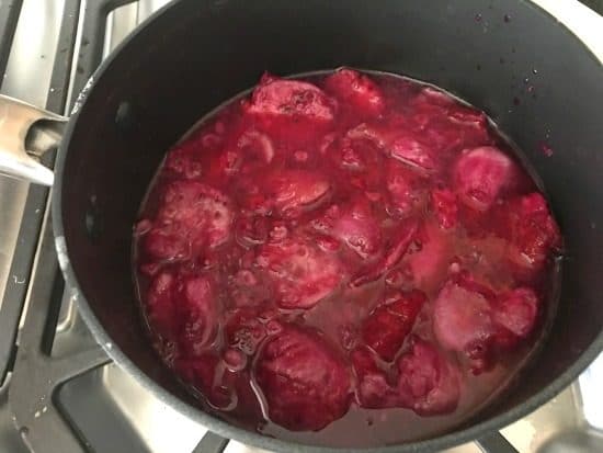 Simmering the prickly pear fruit to reduce the liquid.