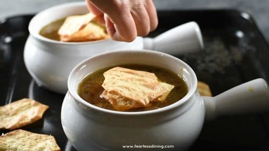 Adding crackers on top of the soup.