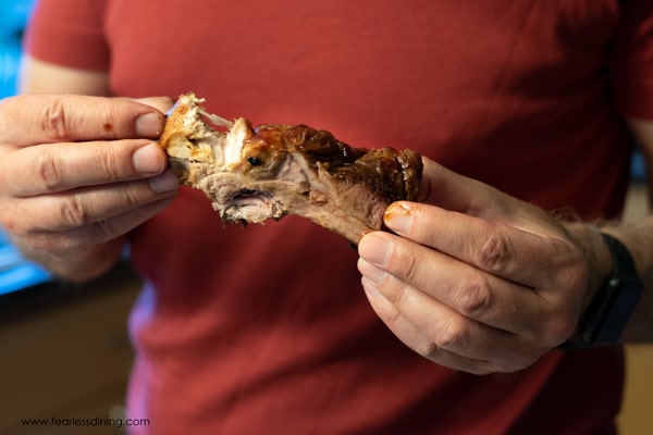 Two hands holding a partially eaten bbq rib.