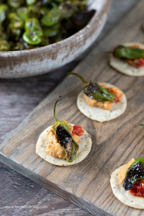 Padron pepper appetizer. The peppers are on top of crackers with roasted red pepper hummus.