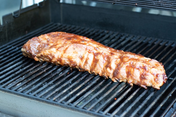 Another shot of the ribs coated in barbecue sauce cooking on the grill.