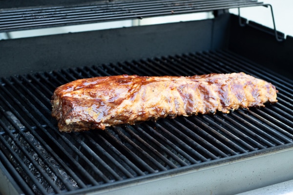 A rack of ribs cooking on a grill.