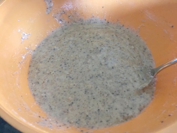 An orange mixing bowl with pancake batter in it.