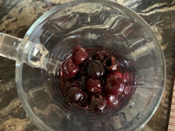 Thawed frozen cherries in a mug.