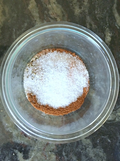 A small glass bowl filled with spice rub for barbecue pork ribs.