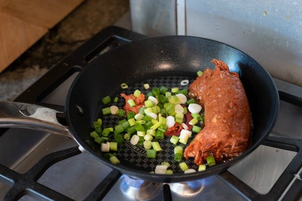 Cooking the chorizo and scallions in a small skillet.