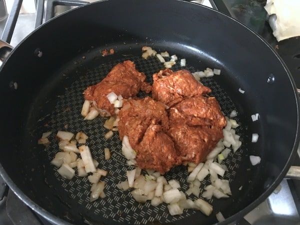 Cooking chorizo and onions in a frying pan.
