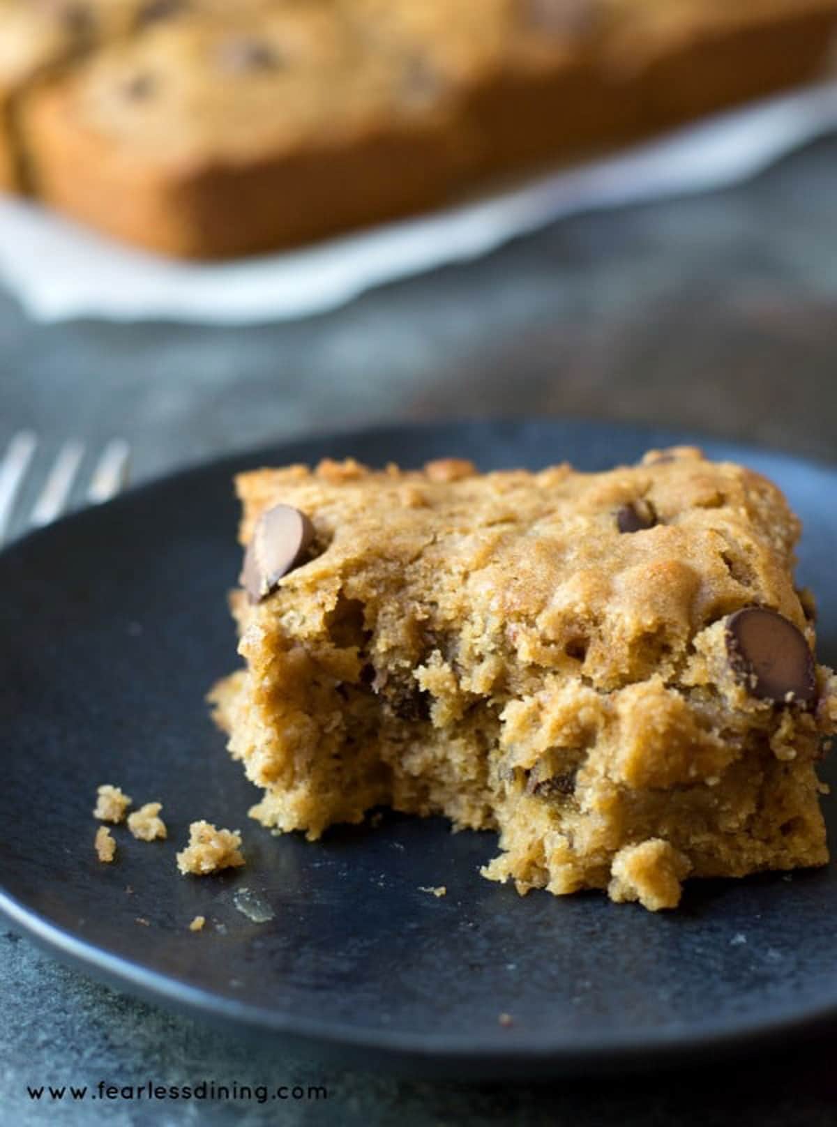 A slice of gluten free banana bar on a small black plate.