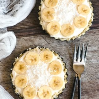 The top view of two yogurt tarts garnished with sliced bananas and shredded coconut.
