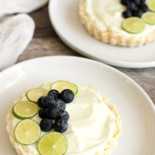 Lime and blueberry topped yogurt tarts on two plates.