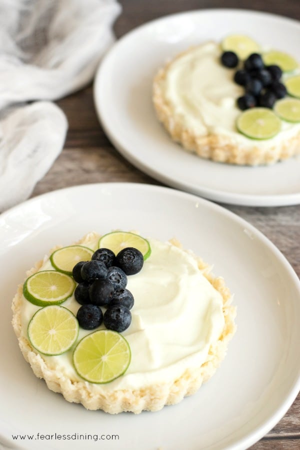 A gluten free fruit tart with key lime slices and fresh blueberries on a white plate.