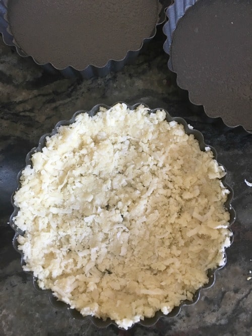 The tart crust in a mini round tart pan.