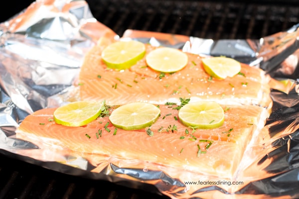 Two pieces of salmon on aluminum foil on the grill.