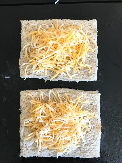 Shredded cheese on slices of gluten free bread.