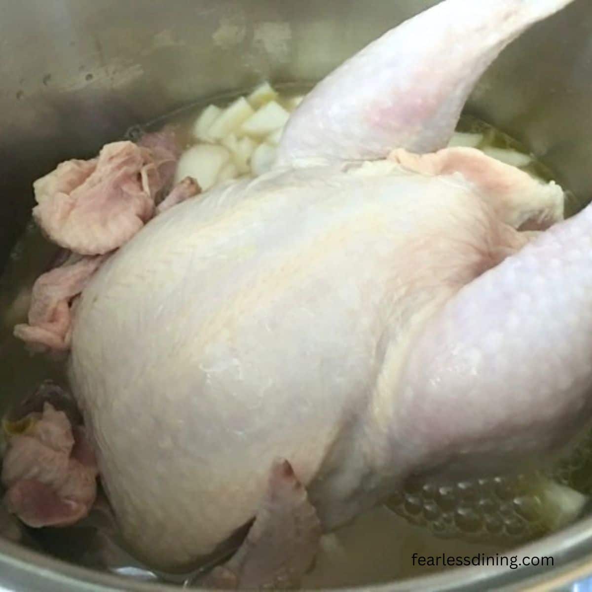 The raw whole chicken and ingredients in the soup pot.