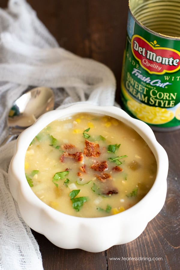 A bowl of corn chowder next to a can of creamed corn.