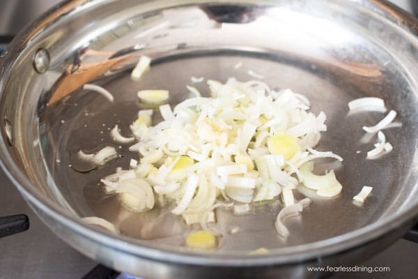 Leeks, oil, and garlic sauteing in a pan.