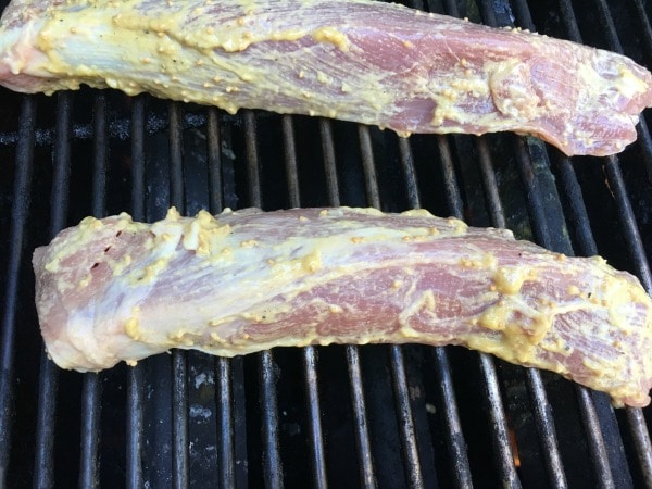 Two pork tenderloins with mustard marinade on a grill.