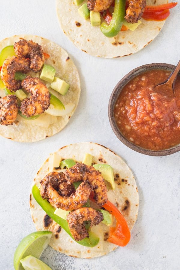 Three blackened shrimp fajitas on a tray with salsa.