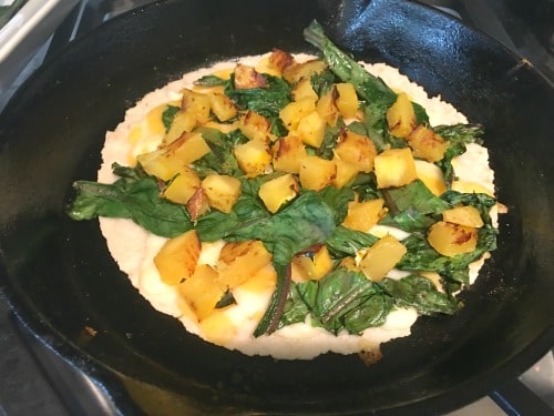 Delicata squash and spinach added to a cooking quesadilla.