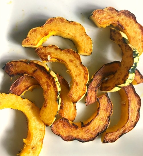 Cooked slices of delicata squash on a plate.