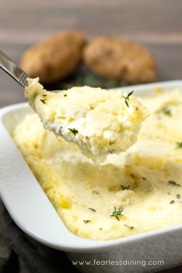 A spoon holding up a serving of mashed potatoes with cream cheese.