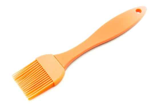 A photo of an orange silicone basting brush.